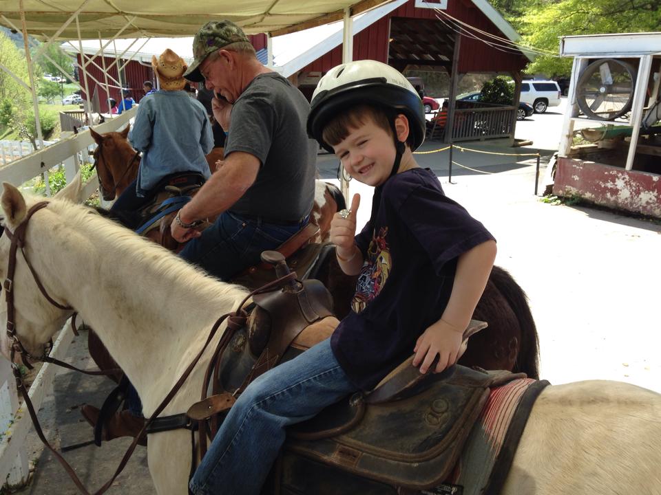 child on horseback giving thumbs-up